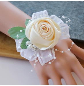 Detail of champagne satin rose wrist corsage with lace and pearls for bridal parties