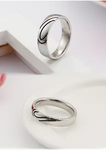Detailed view of silver titanium steel rings with black heart patterns and polished finish