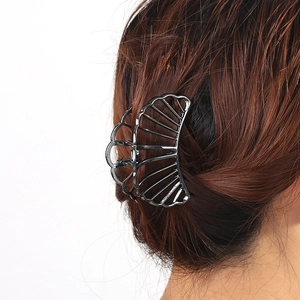 Detail of a large matte black metal hair claw clip with a hollow fan-shaped design