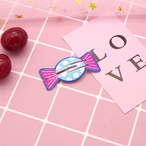 Cute candy-shaped blue polka dot hair clip with pink stripes on a decorative background