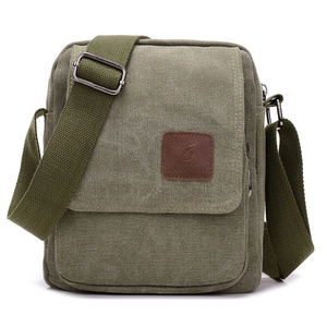 Detail of olive green canvas messenger bag featuring a brown leather logo patch and metal buckle