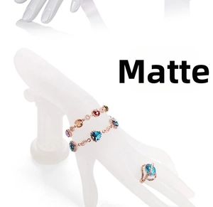 Dettaglio di set gioielli in oro rosa con cristalli a cuore su espositore a mano