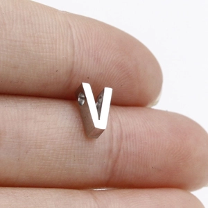 Macro shot of silver V-shaped metal spacer bead held in hand for size reference