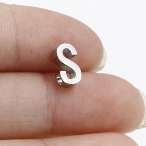 Macro view of small S-shaped stainless steel bead pendant for DIY jewelry making