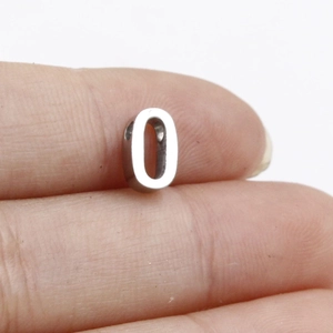 Detail showing a silver number 0 metal bead pendant for DIY jewelry held between fingers