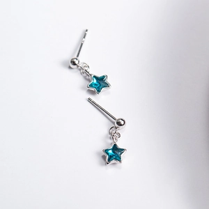 Detail of silver star stud earrings with small blue gemstone pendants on white background