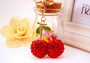 Close-up of sparkling red rhinestone cherry keychain with golden lobster clasp and ring