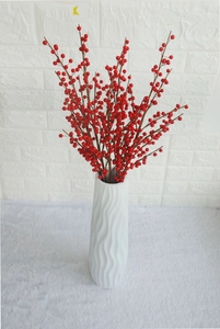 Close-up of artificial red holly berries branches in a white spiral ceramic vase decor