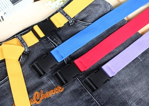 Detail of colorful woven belts with black plastic buckles on grey denim jeans