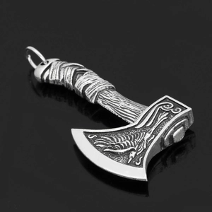 Detail of vintage double-sided Viking axe pendant with Celtic wolf and raven engraving
