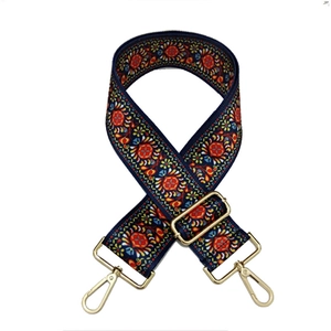 Close-up of wide woven bag strap with colorful floral patterns and gold metal clasps