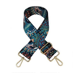 Detail of bohemian style wide bag strap with navy blue patterns and gold metal hooks