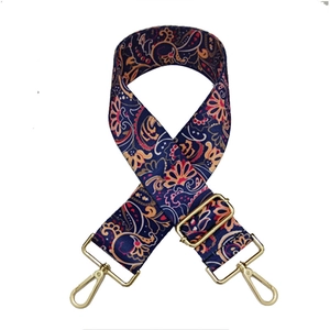Detail of adjustable paisley pattern shoulder strap with gold metal buckles and red accents
