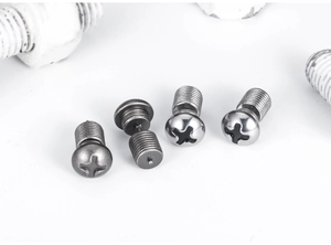 Close-up of industrial screw-style stud earrings in dark gray and silver metal finishes