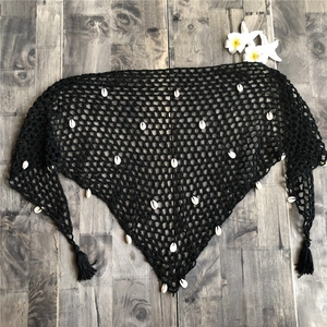 Detalle de chal triangular de ganchillo negro bohemio con conchas reales y borlas