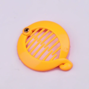 Detail of yellow plastic circular hair clip with fine teeth and metal hinge mechanism