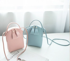 Detailed view of pink and light blue mini crossbody bags with dual zippers and leather texture