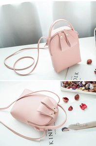 Detailed view of a pink PU leather mini crossbody phone bag on a minimalist desk setup
