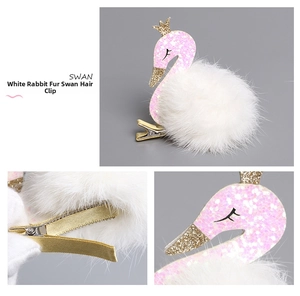 Close-up of a white rabbit fur swan hair clip with pink glitter and gold duckbill clip detail