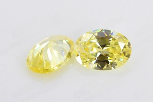 Vue macro de deux zircons jaunes à taille ovale avec un éclat brillant sur fond blanc épuré