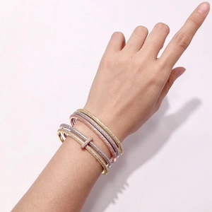 Detailed view of four stacked diamond-encrusted bracelets in gold, silver, and rose gold finishes