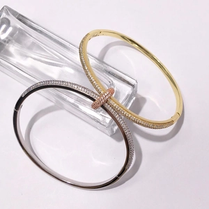 Close-up of gold and silver nail bracelets with micro-pave zircons on a white background