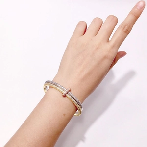 Detail van een vervlochten dubbele armband met pavé-diamanten en gemengde metalen