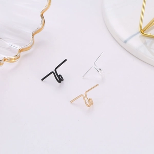 U-shaped alloy ear clips in gold, silver and black colors on a marble surface