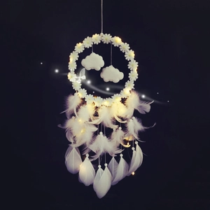 Dream catcher with white feathers, clouds and LED string lights on a dark background