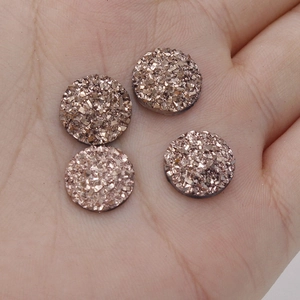 Detailed macro view of 12mm rose gold resin starburst cabochons held in hand for DIY
