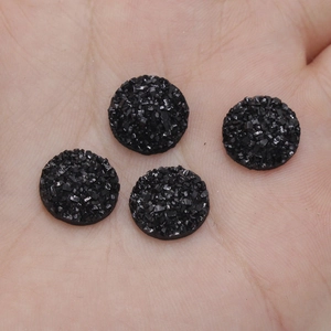 Detailed macro view of 12mm black round resin druzy stones on palm for DIY jewelry