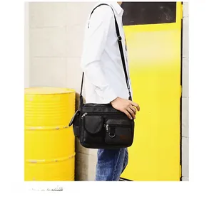 Detail of black canvas crossbody bag showing multi-pocket design and adjustable strap