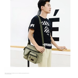 Detail of military green canvas sling bag showing multiple functional zipper pockets