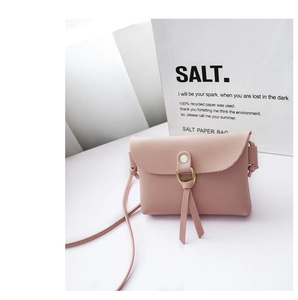 Detail of pink mini crossbody bag with gold ring buckle and elegant leather tassels