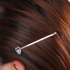 Close-up of a silver owl hair clip with crystal accents worn on brown hair