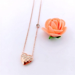 Detailed view of a rose gold heart necklace with crystals on a white background