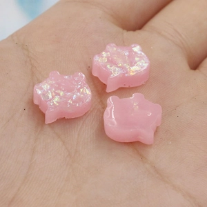 Macro view of three pink pig-shaped opal stones for DIY jewelry making held in a hand