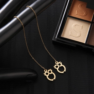 Detailed view of gold owl dangle threader earrings suspended on a black display stand