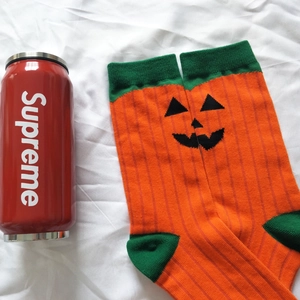 Detail view of Halloween pumpkin socks in vibrant orange and green knitted cotton fabric