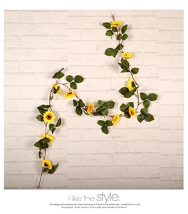 Detail of lifelike yellow sunflower garland with green leaves for home wall decoration