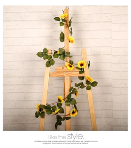 Detailed view of artificial sunflower vine with yellow petals and green leaves on easel