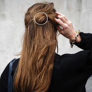 Close-up of a gold metal circular hair clip worn by a model in a half-up hairstyle