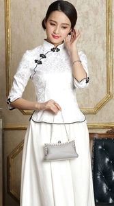Silberne Perlen-Abendtasche, gehalten von einer Frau im weißen Cheongsam mit schwarzen Details