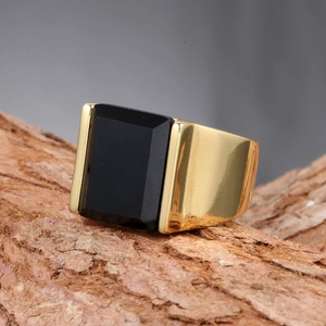 Détail macro d'une bague pour homme dorée avec une grande pierre noire facettée sertie