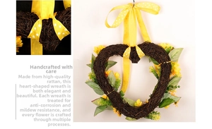 Détail d'une couronne de tournesols en forme de cœur avec ruban jaune et base en vigne