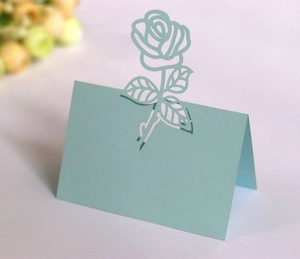 Detail of light blue laser-cut rose place card for weddings with hollow floral design