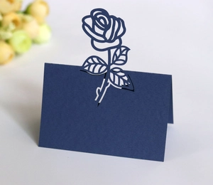 Macro detail of navy blue laser-cut rose hollow place card in premium pearlescent paper
