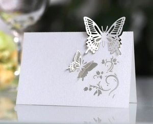 Detail of laser-cut hollow butterfly place card with intricate floral patterns for weddings