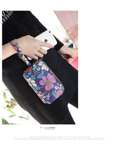 Detailed view of a purple floral wristlet purse with three zippers and wrist strap