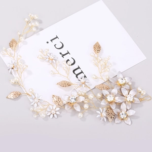 Dettaglio di un accessorio per capelli da sposa con fiori dorati, perle e cristalli